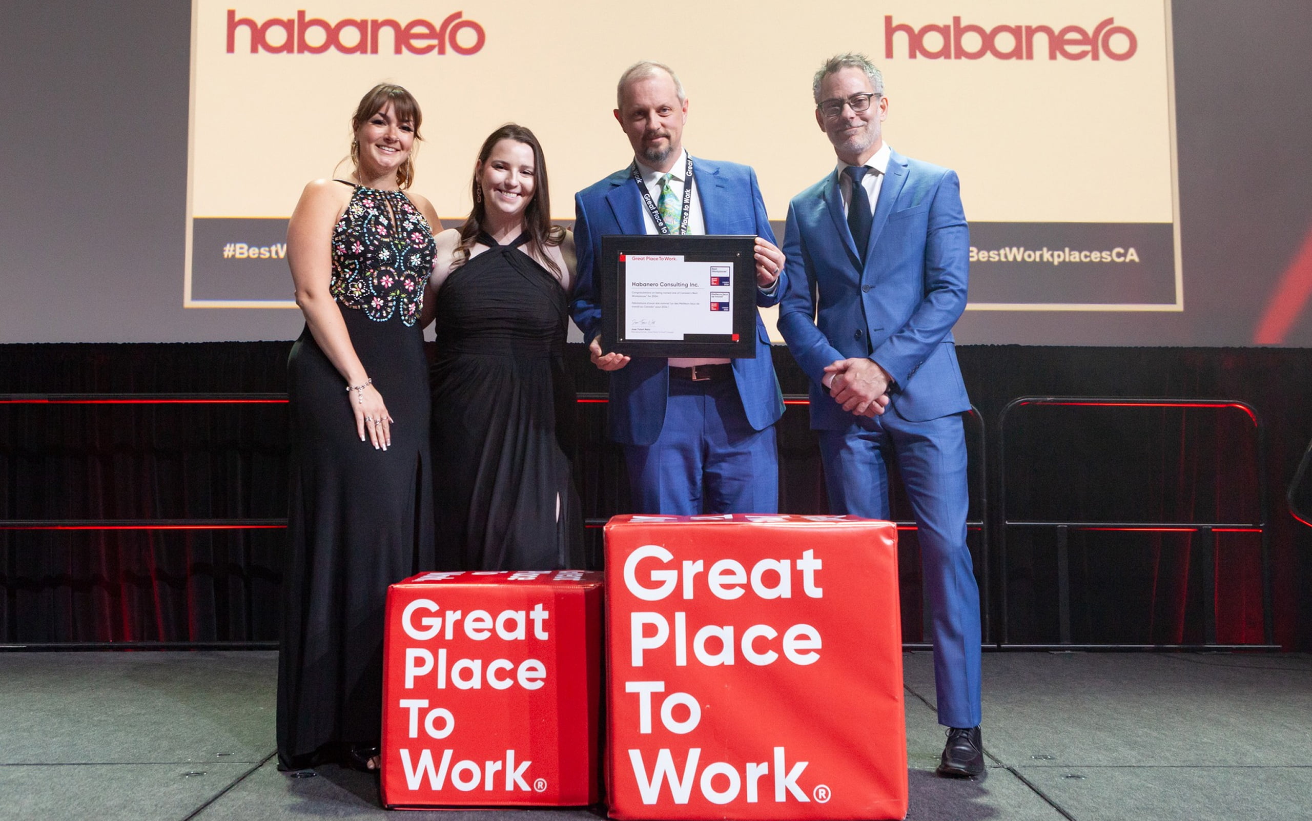 Two women and two men from Habanero Consulting holding an award from Great Place to Work Canada.
