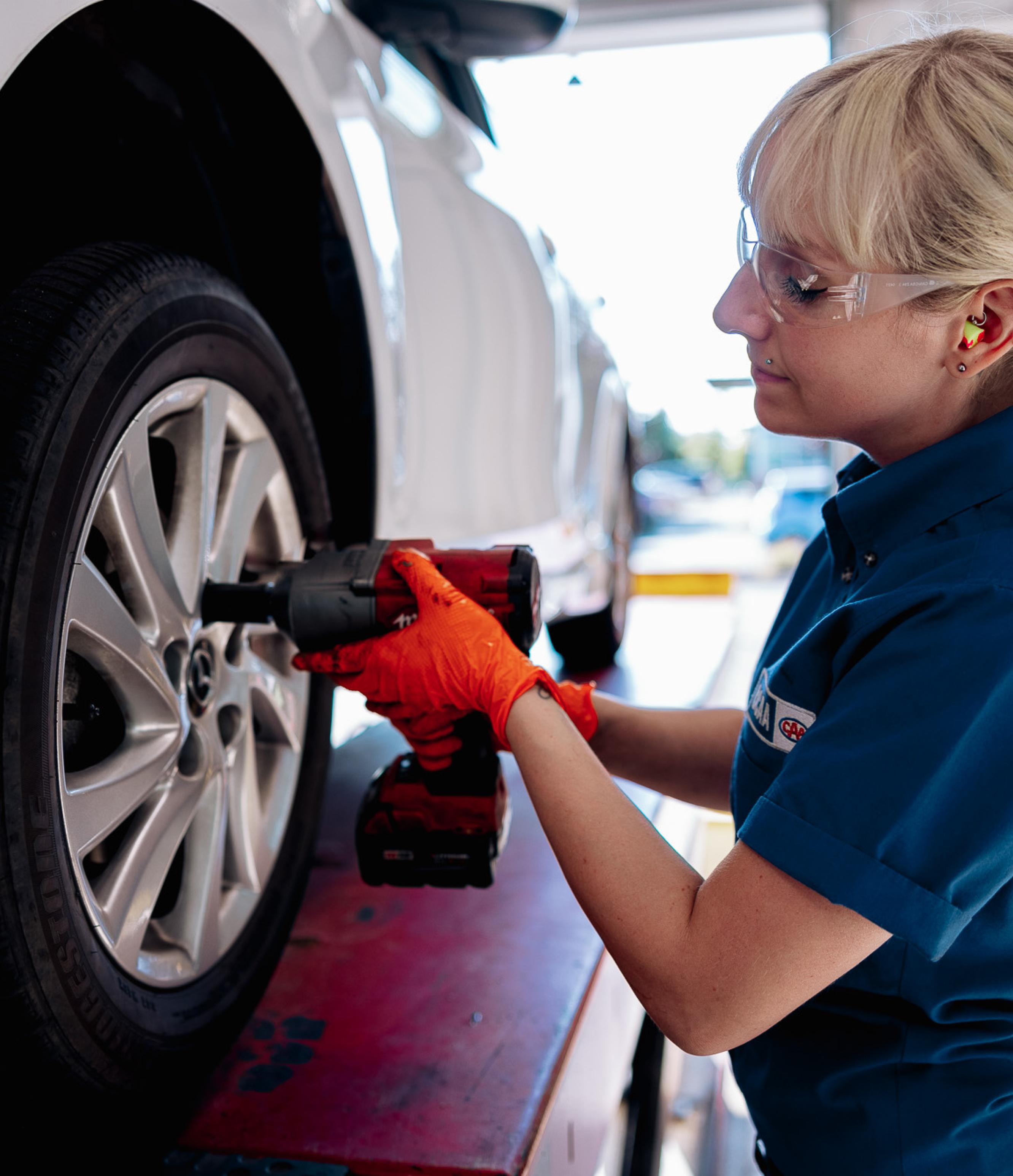 A mechanic putting on a tire of a car.