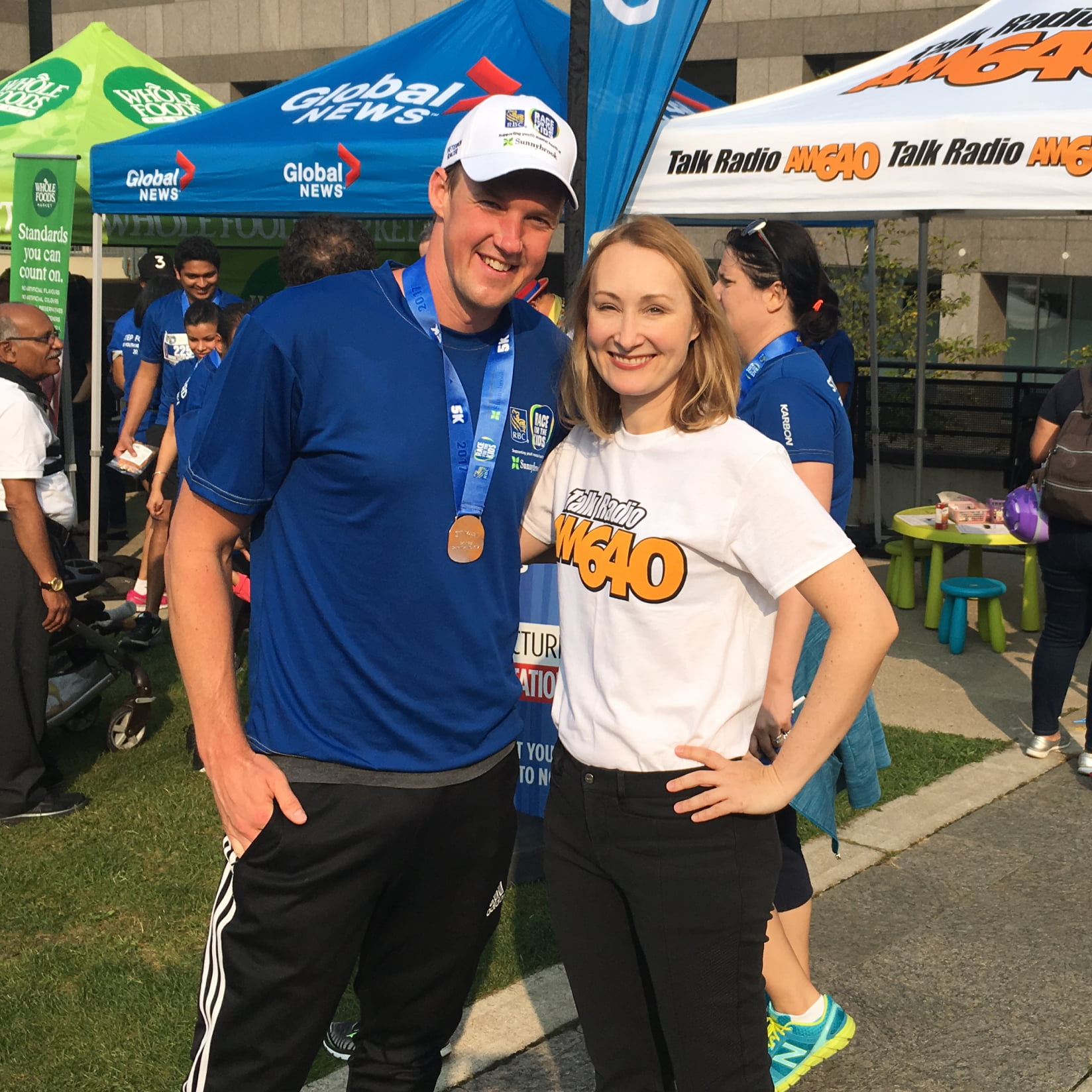 Image of a man and a woman outside at an event, smiling at the camera.